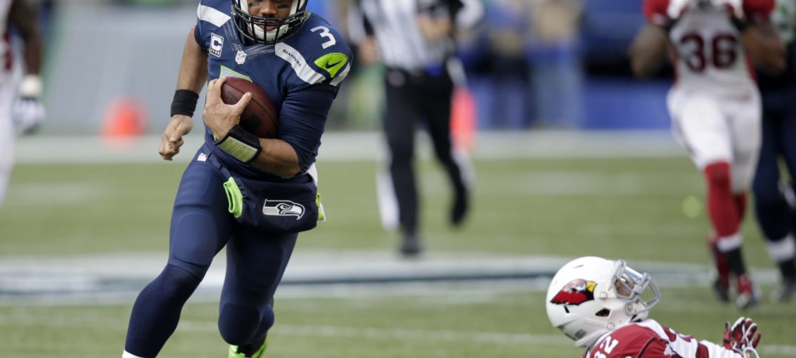 Seattle Seahawks quarterback Russell Wilson stiff arms Tampa Bay Buccaneers  cornerback Michael Adams (21) on his way to a first down in the third  quarter at CenturyLink Field in Seattle, Washington on